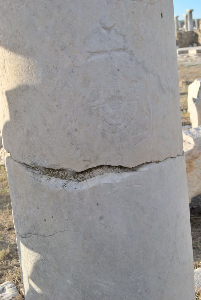 A column with a cross and a menorah carved into it.